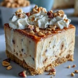 A rich Nutter Butter Cheesecake garnished with chopped peanuts and a whole cookie sits on a rustic wooden serving board.
