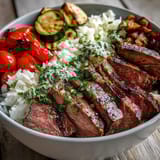 Sliced steak and vibrant chimichurri sauce top this Grilled Steak Bowl.