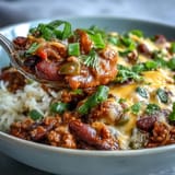 A hearty bowl of Chili Bowl Base garnished with sour cream, green onions, and fresh cilantro.