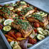 Freshly chopped parsley and lemon wedges garnish this easy, gluten-free Sheet Pan Salmon and Veggies Bowl, highlighting the colorful medley of roasted vegetables.