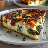 Spring Brunch Frittata with Asparagus and Goat Cheese, golden and fluffy, topped with fresh herbs and creamy cheese.