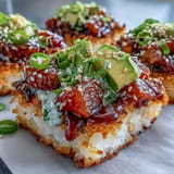 A vibrant sushi-inspired salad with crunchy rice squares, fresh avocado, and bold spicy tuna, drizzled with tangy sesame dressing.  