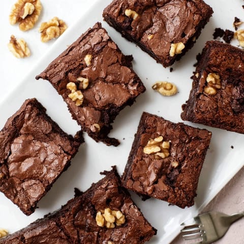 Warm brownies are served à la mode with a scoop of vanilla ice cream melting on top.