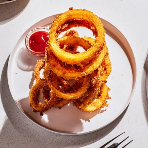 Deep-fried onion rings with a light, crunchy batter served hot alongside a burger. 