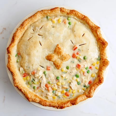 Slices reveal creamy chicken, carrots, and peas inside this classic American comfort food dinner.