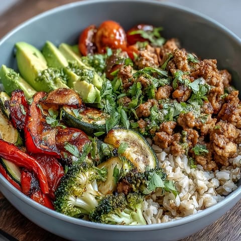 Ground Turkey Bowl with roasted veggies, avocado, and cilantro on a wooden table.
