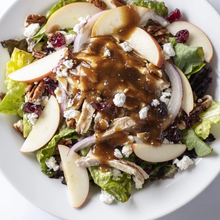 Freshly made caramel-pecan dressing is drizzled over the autumn salad, showcasing its glossy texture and glistening pecans.