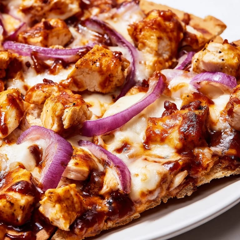 Rustic BBQ Chicken Flatbread with grilled chicken, sweet red onions, and cilantro garnish, bubbling with cheese on a golden, crispy flatbread base.