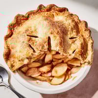 Golden, flaky Apple Pie slices reveal cinnamon-spiced apple filling and a buttery, crimped crust, served warm.