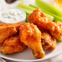 Golden-brown crispy Buffalo Wings tossed in tangy red sauce with celery sticks and blue cheese dip on the side.